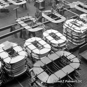 黑白照片显示一家工厂制造椭圆形成型机以固定电力变压器中的铜线。
