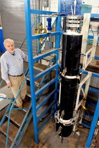 南伊利诺伊大学煤炭研究中心的助理主任站在一个将少量煤分离成合成气的模型气化系统旁边。查看更多绿色科学图片。