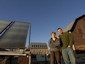 丽莎·基维里斯特（Lisa Kivirist）和约翰·伊万科（John Ivanko）站在一个太阳能热系统旁边，该系统在他们的住宿加早餐旅馆为温室供暖。